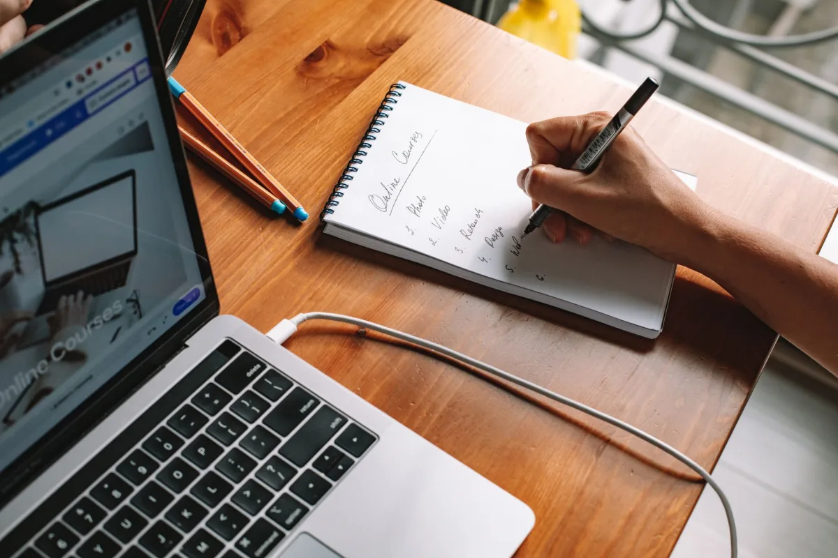 Pessoa estudando um curso online com notebook e anotações